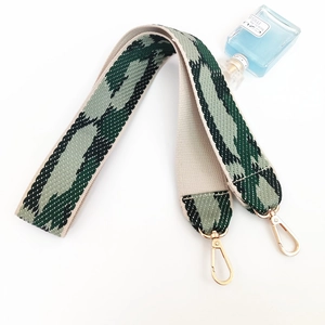 Detail of wide woven strap with green python pattern and gold metal spring hooks