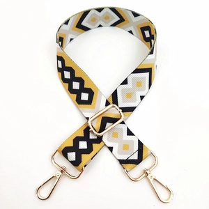 Close-up of geometric woven shoulder strap with gold metal lobster clasps and buckles