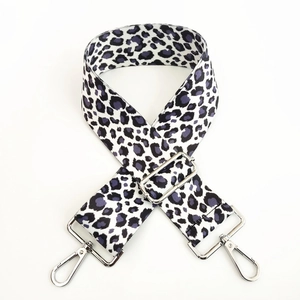 Dettaglio tracolla leopardata con fibbie metalliche argentate su sfondo bianco neutro