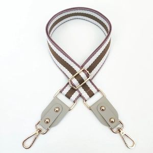 Détail macro de la bandoulière tressée rayée marron et blanc avec boucles dorées champagne