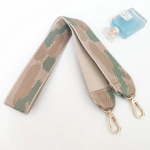 Close-up of wide camouflage woven bag strap with premium gold lobster clasps and texture