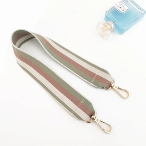 Detail of wide woven shoulder strap with green and pink stripes and gold lobster clasps