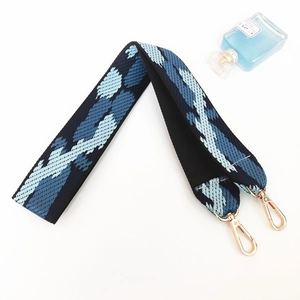 Close-up of wide multi-color woven bag strap with golden buckles on a white background