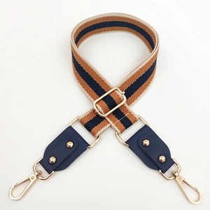 Détail d'une bandoulière tissée réglable à rayures brunes et boucles dorées