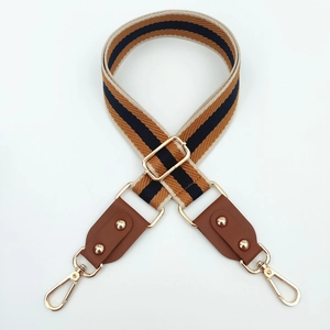 Détail de la bandoulière tissée réglable avec cuir marron et mousquetons dorés brillants
