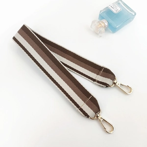 Close-up of striped wide replacement shoulder strap with gold lobster clasps and brown tones