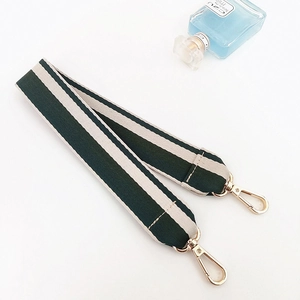 Close-up of green and beige striped fabric bag strap with shiny gold lobster clasps