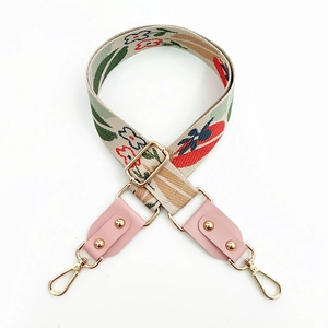 Detail of floral embroidery strap with leather ends and golden metal snap hooks