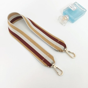 Detail of multi-color striped canvas bag strap with gold metal hooks on white background