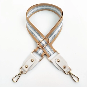 Detail of adjustable striped bag strap with metallic silver thread and gold metal rivets