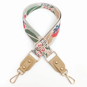 Detail of bohemian jacquard flower strap with gold metal hooks and beige leather ends