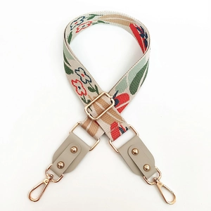 Detail of adjustable floral woven bag strap with gold buckles and grey leather ends