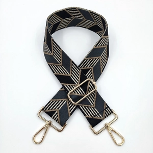 Detail of wide adjustable jacquard strap with geometric arrow pattern and gold metal hooks
