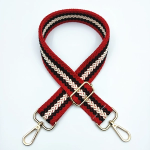 Détail de la bandoulière tissée à rayures rouges et noires avec des crochets dorés