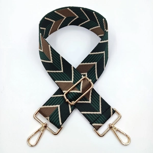 Detail of adjustable woven bag strap with green geometric pattern and gold metal hooks