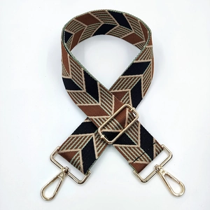 Detail of wide woven jacquard shoulder strap with geometric diamond patterns and gold hooks