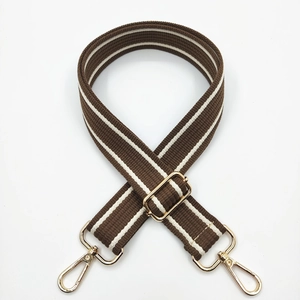 Detail of a brown and white striped wide cotton shoulder strap with gold metal buckles