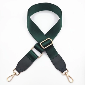 Detail of dark green nylon bag strap with gold metal buckles and black leather ends