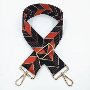 Detail of wide woven strap with geometric arrow pattern and gold metal hardware