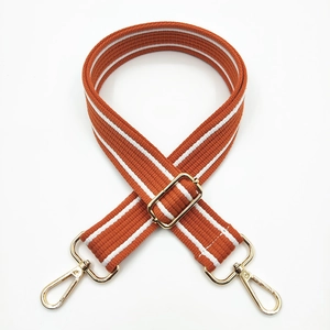 Detail of adjustable orange and white striped cotton shoulder strap with gold metal hooks