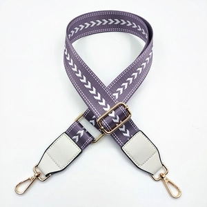 Close-up of purple nylon bag strap with white arrow pattern and golden metal hardware