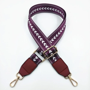 Detail of adjustable nylon bag strap with white chevron pattern and gold metal hooks