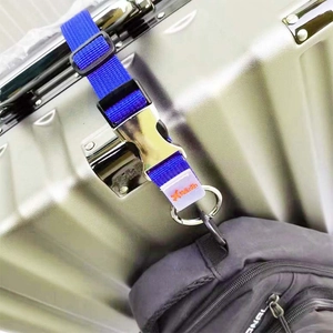 Détail d'une sangle de bagage bleue avec boucle en métal fixant un sac à dos à une valise