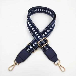 Detail of navy nylon bag strap with white arrow pattern and golden metal swivel hooks