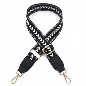 Detail view of nylon bag strap with white arrow embroidery and gold metal lobster clasps
