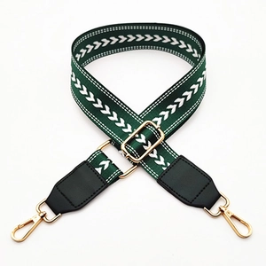 Detail of adjustable green nylon strap with white arrow embroidery and gold lobster clips