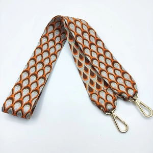 Close-up of ethnic jacquard bag strap with silver thread geometric pattern and gold clips