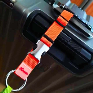 Détail d'une sangle de bagage en nylon orange avec boucle métallique sur une valise