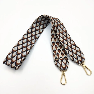 Close-up of geometric jacquard bag strap with golden lobster clasps and leather ends