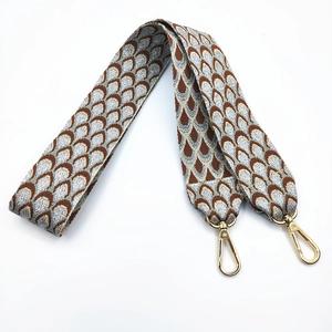 Detail of embroidered jacquard bag strap with ethnic scale pattern and gold lobster clasp