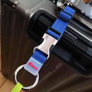 Détail d'une sangle de valise en nylon bleu avec boucle métallique sur une valise noire