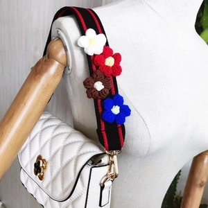 Close-up of a white quilted crossbody bag with 3D colorful crochet floral shoulder strap