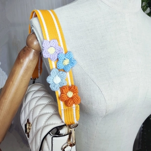Close-up of a wide yellow striped fabric strap with colorful crochet flower decorations