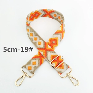 Detail of 5cm wide geometric woven bag strap with orange diamond patterns and gold hooks