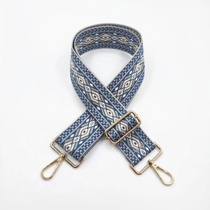 Macro detail of adjustable jacquard bag strap with geometric patterns and gold metal buckles