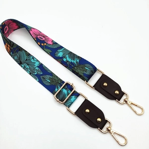 Close-up of adjustable strap with floral patterns, leather ends and gold metal hooks