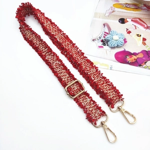 Detail eines rot-weißen Tweed-Gurtbands mit goldenen Beschlägen und Fransenkanten