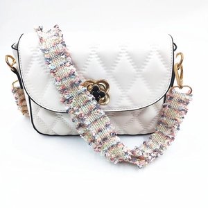 Detail der weißen gesteppten Ledertasche mit gewebtem Tweed-Gurt und Kleeblatt-Schloss