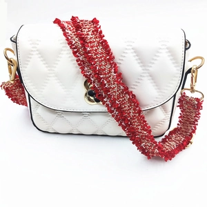 Detail der weißen Stepptasche mit verstellbarem rot-goldenen gewebten Quastenschultergurt