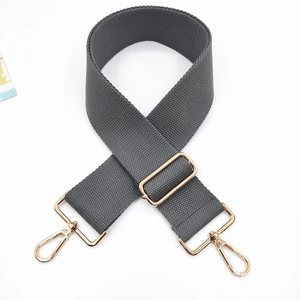Detail view of a gray nylon shoulder strap with gold metal buckles and lobster clasps
