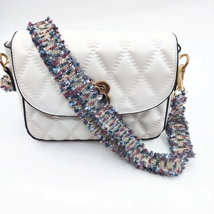 Detail der weißen Stepptasche mit buntem Tweed-Quastenriemen und Herzverschluss in Gold