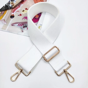 Detail of white wide woven adjustable shoulder strap with gold metal buckles and waffle texture