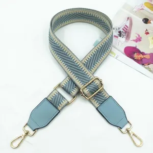 Detail of adjustable blue and beige crossbody strap with golden metal lobster hooks
