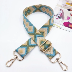 Detail of bohemian geometric jacquard strap with golden lobster clasps and buckle