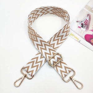 Detail of adjustable geometric brown and white embroidered wide strap with gold metal hooks