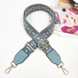 Detail of blue geometric embroidered bag strap with light blue leather and gold hardware